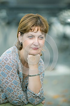 Middle-aged woman sits on a bench in a public garden