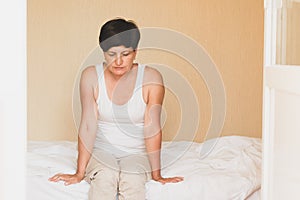 A middle-aged woman is sitting in bed, depressed. Women& x27;s health depression sleep problems sadness loneliness.