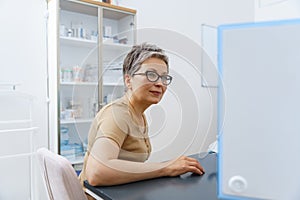 Middle aged woman sitting in doctor& x27;s office during appointment and looking at side
