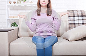 Middle aged woman sitting on the sofa at home background. Copy space and mothers day. Menopause and dieting.
