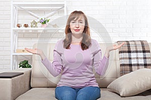 Middle aged woman sitting on the sofa at home background. Copy space and mothers day. Menopause