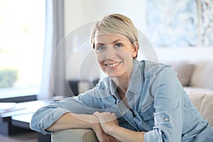 Middle-aged woman sitting on sofa at home