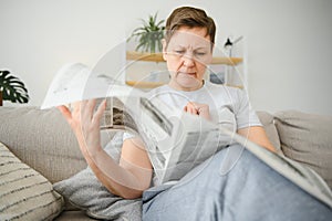 middle aged woman sitting sofa and reading newspapers.