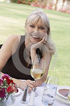 Middle Aged Woman Sitting With Wineglass At Outdoor Table