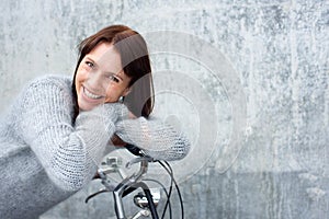 Middle aged woman smiling and leaning on bicycle