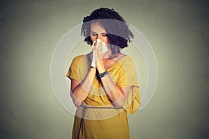Middle aged woman sneezing in a tissue blowing her runny nose