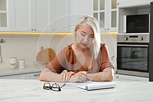 Middle aged woman solving sudoku puzzle at table