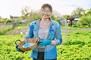 Middle-aged woman in spring garden, in gloves with shovel and seeds in packs