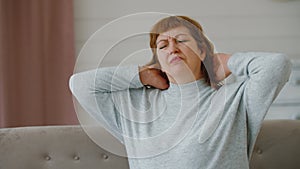 Middle aged woman suffering from neck pain, older lady massages neck muscles