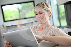Middle-aged woman on tablet websurfing photo