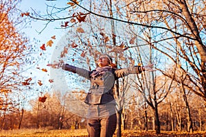 Middle-aged woman throwing leaves in autumn forest. Senior woman having fun outdoors