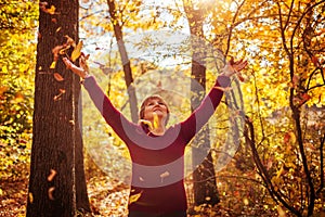 Middle-aged woman throwing leaves in the forest