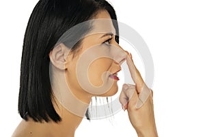 Middle aged woman touches her nose with her finger on a white background