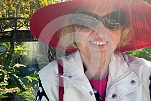 Middle-aged woman tourist wearing in red hat and sunglasses on waterfall with rainbow in jungles background