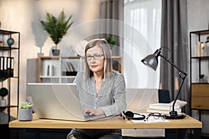 Middle-aged woman typing on computer in home office