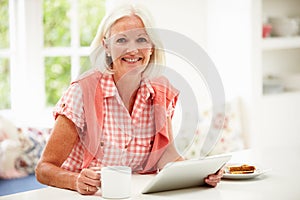 Middle Aged Woman Using Digital Tablet Over Breakfast