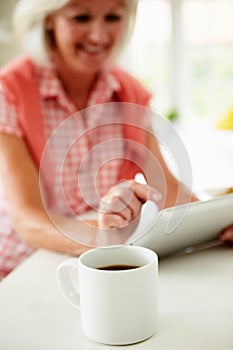 Middle Aged Woman Using Digital Tablet Over Breakfast