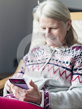 A middle aged woman,using her smartphone,at home,checking up on friends,Worcestershire,England,UK