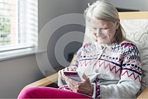 A middle aged woman,using her smartphone,at home,checking up on friends,Worcestershire,England,UK