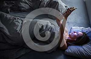 Middle-aged woman using her tablet computer before sleep in bed in the evening