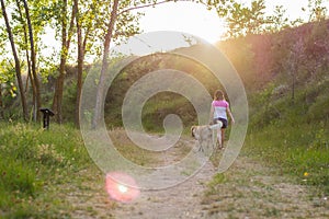 Middle-aged woman walking with her dog on a mountain path