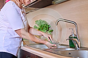 Middle aged woman washing dishes at home kitchen