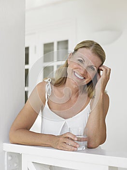 Middle Aged Woman With Water Glass On Verandah