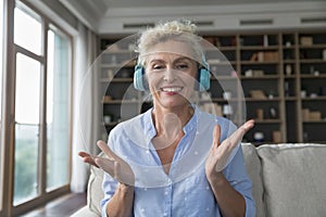 Middle-aged woman wear headphones talking on video conference