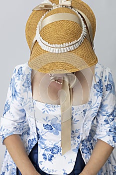 A middle-aged woman wearing an 18th-century English gown with a straw hat