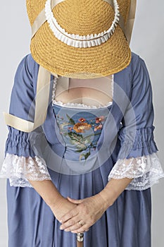 A middle-aged woman wearing an 18th-century robe a la Francaise and a straw hat