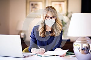 Middle aged woman wearing face mask for prevention while working from home