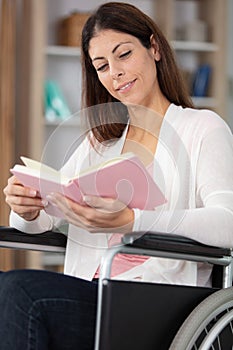 middle aged woman in wheelchair reading book