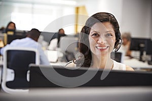 Middle aged woman working at computer with headset in office