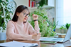 Middle-aged woman working at computer laptop in home office