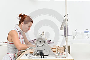 Middle aged woman works at a sewing machine in a sewing workshop