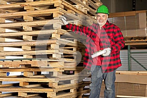 Middle aged working standing in front of wooden pallets