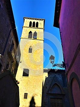 Middle Ages tower, pink building and shadows in Vitorchiano town, Italy