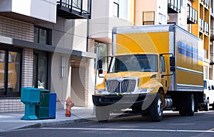 Middle class yellow semi truck with box trailer on city street f