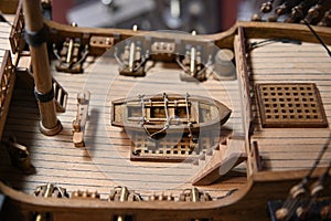 Middle deck of a wooden ship model. There is a dinghy in the center of it