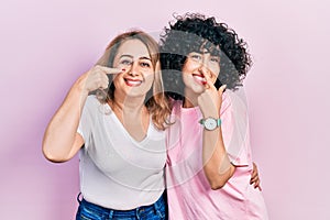 Middle east mother and daughter wearing casual clothes pointing with hand finger to face and nose, smiling cheerful