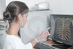 middle east woman doctor looking at monitor with chest bones computer tomography image and pointing at details. female