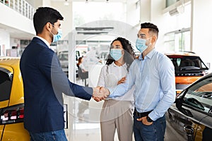 Middle-eastern couple shaking salesman hand, buying new car