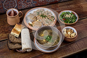 Middle Eastern cuisine dishes in ceramic plates on a wooden table. Lentil soup, salad with lettuce and tomatoes, kufta with spelt