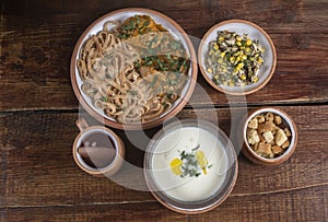 Middle Eastern cuisine dishes in ceramic plates on a wooden table. Soup with Greek yogurt, chicken with onion sauce, herbs and