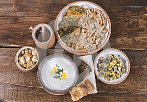 Middle Eastern cuisine dishes in ceramic plates on a wooden table. Soup with Greek yogurt, chicken with onion sauce, herbs and