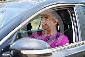 A middle eastern dark skin senior retired man driving a car, portrait from the side.