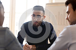 Middle eastern ethnicity young businessman listening to multiracial partners.