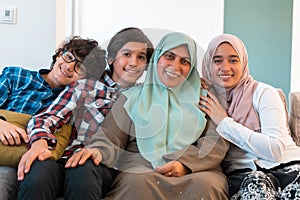 Middle eastern family portrait single mother with teenage kids at home in living room. Selective focus