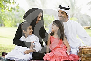 A Middle Eastern family sitting in a park