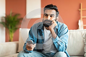 Middle eastern guy switching television channels sitting at home